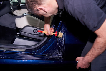 A man washes a blue car. Thorough washing of the body with foam and a high-pressure apparatus