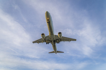 An isolated comercial airliner in the blue and cloudy sky from below