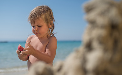 Little caucasian girl making sand sculpture on sea holiday