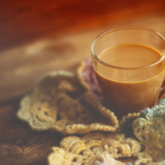 Coffee with milk wrapped in warm white knitted scarf and flowers tagetes on white wooden table. Mood of warmth and comfort. Seasonal autumn concept. Square image