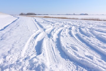 Fototapeta na wymiar Car tracks in the snow in winter landscape