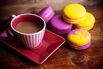 Fototapeta na wymiar colored macaroons and a Cup of coffee on a wooden table, color macaroons ultraviolet