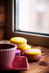 colored macaroons and a Cup of coffee on a wooden table, color macaroons ultraviolet