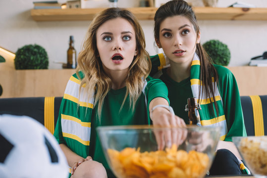 Shocked Female Football Fans In Green T-shirts And Scarf Gesturing By Hands During Watch Of Soccer Match At Home