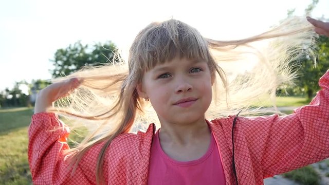 Cute little kid girl portrait play with her hair in sunset sun rays slow motion