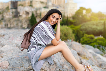 Städtereise Konzept: attraktive Frau mit Rucksack sitzt auf den Felsen vor der Akropolis in Athen, Griechenland and einem Sommertag