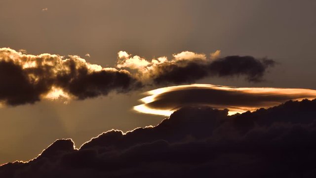 Dark cloud formations moving Left to Right backlit by setting sun.