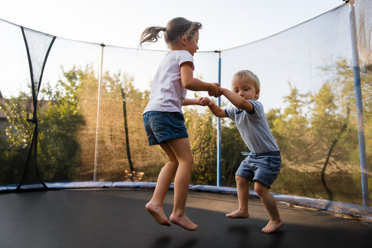 Adorable siblings bouncing together on trampoline