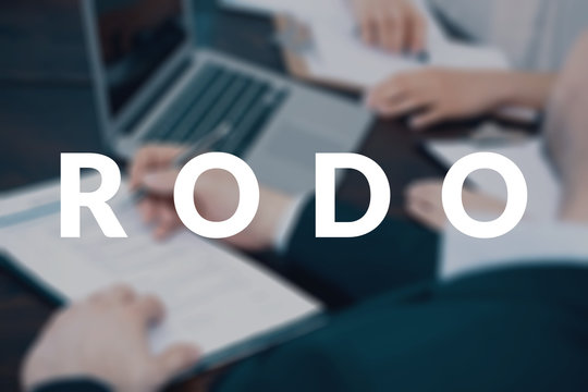 Businessmen working on a laptop, creating a new company data protection policy. RODO concept. Blurred photo with white text