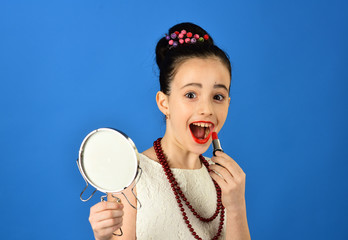 childhood and happiness childhood, little girl pit red lipstick on lips with mirror