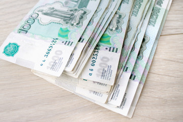 business, finance, saving, banking concept - close up bundle of money Russian Banknotes thousand rubles on wooden table