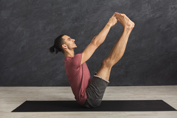 Young man practicing yoga with gymnastic mat
