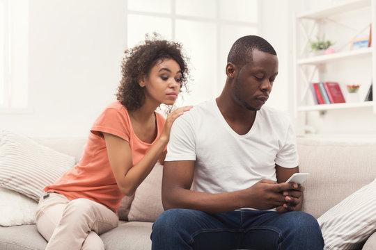 African-american couple at home, man texting