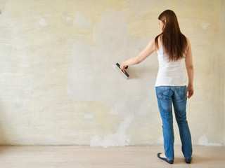 Woman plastering the walls with finishing putty in the room.