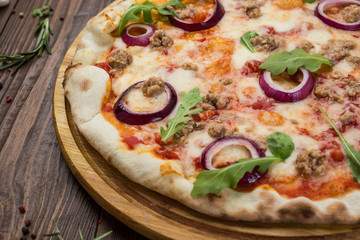 Minced meat tomato red onion pizza on a wood background