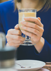 Woman in blue dress holding hot cup of coffee.
