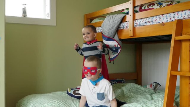 Slow motion of two cute brothers in capes playing super heros