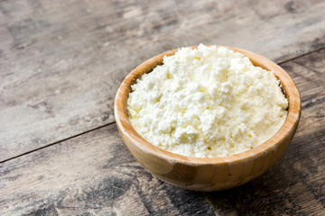 Fresh cottage cheese in a wooden bowl on wooden table
