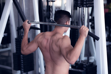Portrait of young man using weight lifting equipment , bodybuilder concept.