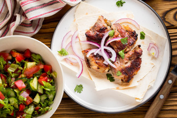 Kebab, pieces of meat, beef, pork on thin pita with onion, salad