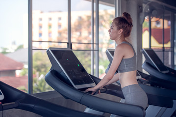 Attractive young sports woman running on treadmill in gym, health care concept.