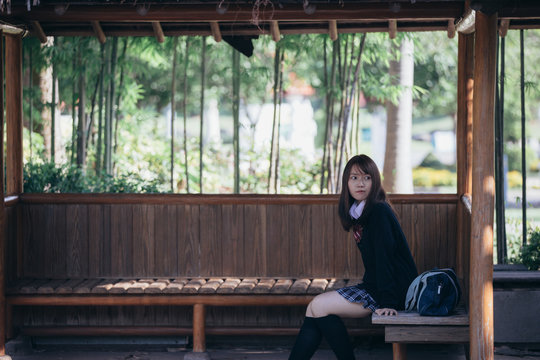 Portrait young japanese school girl sitting in japanese garden and bamboo forest