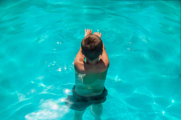 Boy exercising in outdoor swimming pool, learning to swim