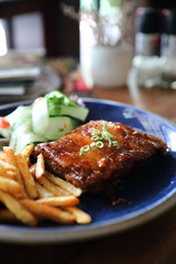 barbecued pork ribs steak with fresh vegetables on an old rustic wooden in restaurant