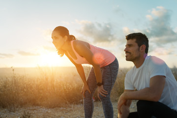 Running motivation and healthy fitness lifestyle. Couple of athletes resting during outdoor sunset workout.