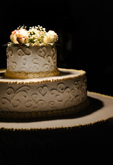 Obraz na płótnie Canvas Bellissima torta nuziale di panna ornata con dei fiori in cima - sfondo nero