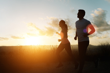 Two athletes running at sunset. Backlit silhouette of man and woman training together. - 208111598