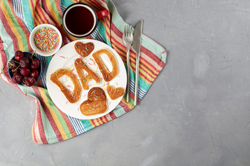 Special Father's Day breakfast. Alphabet Pancakes with sprinkles, cherries and cup of tea on a gray concrete background