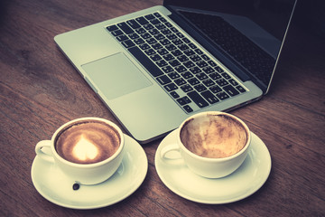 Empty cups and full coffee cup placing together with laptop on the desk
