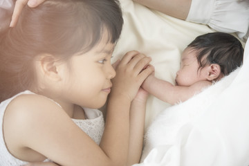 Obraz na płótnie Canvas Happy girl playing with her newborn sister