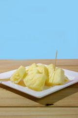 A slice of pineapple on wooden table in cyan background verticle. 