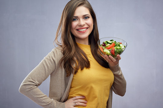 Smiling girl holding glass bowl with healthy food salad.