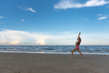 Fototapeta na wymiar Young healthy woman with blonde curly hair practicing yoga on the beach, Summer beach vacation and relaxing concept.