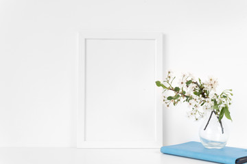 White frame mock up with spring cherry bouquet and blue notebook. Mock up for your photo, design or text.