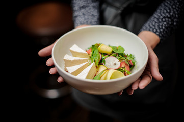 Girl holding a white bowl with a fresh salad