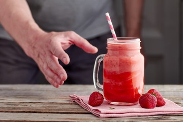 Men hand, taking the jar with yogurt and strawberry smoothie