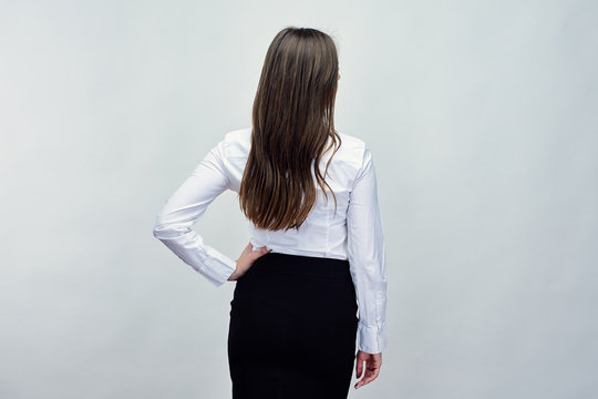 Woman with long hair wearing white shirt and black skirt standin