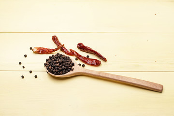 The dried chili put beside wooden spoon with pepper seed,on yellow wooden timber board,blurry light around.