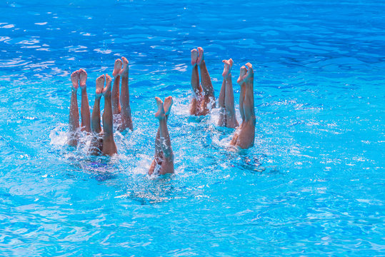 Artistic Swimming. Beautiful Lean Female Legs In The Water Of A Swimming Pool. Concept Of Beauty, Artistry, Athleticism And Synchronicity.