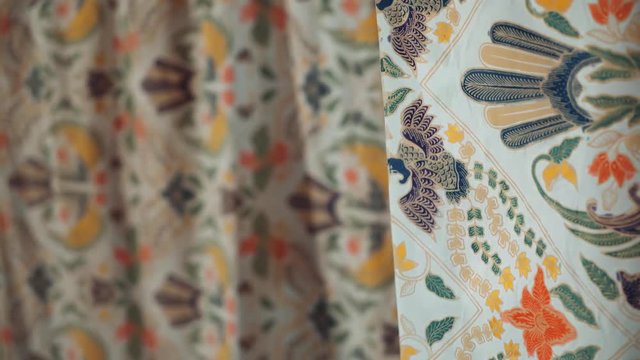Close up of young caucasian woman hand touching batik fabric