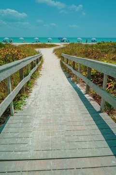 Dramatic vertical view of Wood Bridge looking toward a sandy Sanibel Beach on Sanibel Island with colorful umbrellas on a sunny day before Hurricane Ian