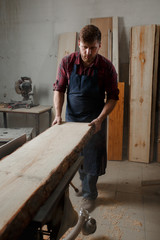 Master carpenter saws the board on machine in workshop