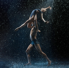 Young couple of ballet dancers dancing unde rwater drops