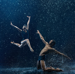 Young couple of ballet dancers dancing unde rwater drops