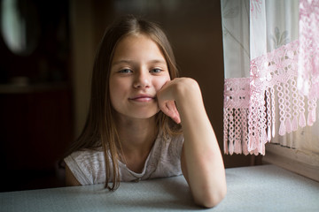 Portrait of cute ten-year-old girl sitting at the table.