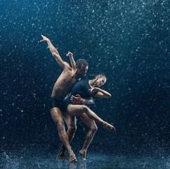 Young couple of ballet dancers dancing unde rwater drops